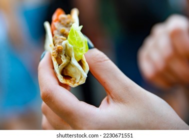 woman hand holding mini taco traditional in mexican food. street food