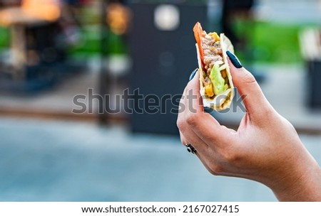 woman hand holding mini taco traditional in mexican food. street food