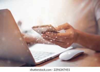 Woman hand holding mobile phone and laptop data synchronization device at co-working office, She using in mobile applications and multimedia programs. - Shutterstock ID 2296347451