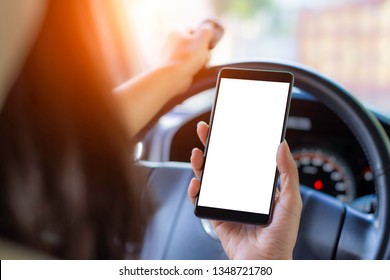 Woman hand holding mobile smart phone with blank white screen and using remote control to open the auto door while driving car. Safety system and automatic gate concept.