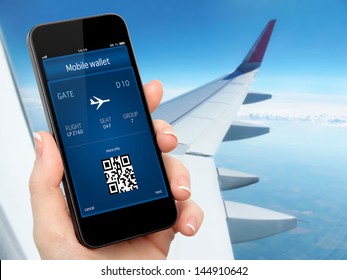 Woman Hand Holding The Phone With Mobile Wallet And Plane Ticket Against The Background Of The Window With Blue Sky And Airplane Wing