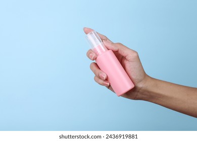 Woman hand holding pink blank small spray bottle mockup isolated on blue background