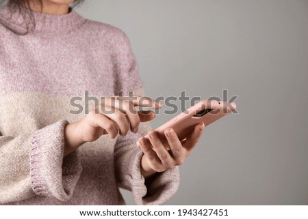 woman hand holding pink phone on grey background