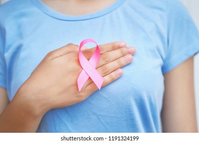 woman hand holding pink ribbon on chest.healthcare and medicine concept. breast cancer awareness                                - Shutterstock ID 1191324199