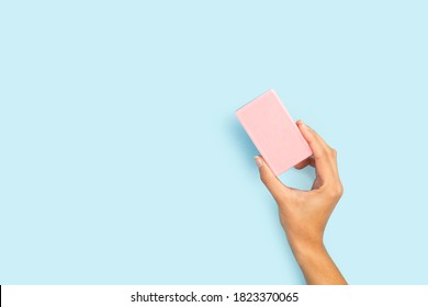 Woman Hand Holding A Pink Soap Bar On A Light Blue Background