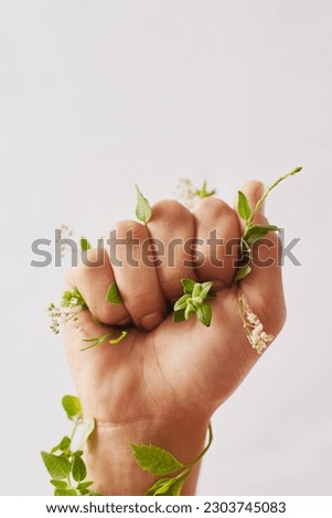 Woman hand, holding plants and fist for eco warrior, fight and revolution for sustainability protest. White background, studio and person with leaf and green plant in hands for environment rally