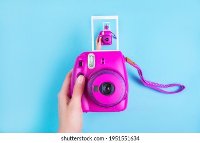 Woman Hand Holding Purple Instant Camera Isolated On Blue Background.