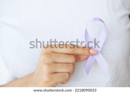 Woman hand holding purple ribbon bow, lupus LSE or alzheimer awareness symbol