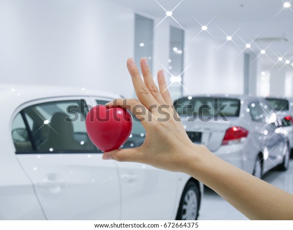 woman hand holding a red heart in Underground\
parking with cars.
