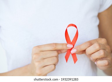 Woman hand holding red ribbon HIV, world AIDS day awareness ribbon.