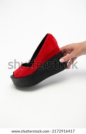Woman hand holding red summer shoe isolated on white, copy space