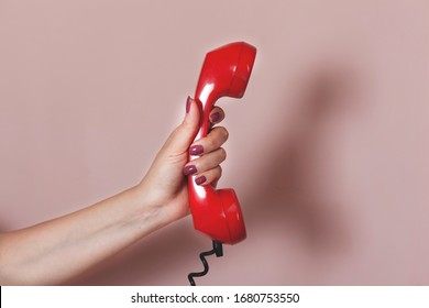 Woman Hand Holding Red Vintage Phone On Pink Background