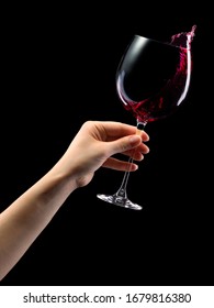 Woman Hand Holding Red Wine Glass With Splashes Isolated On Black Background With Clipping Path