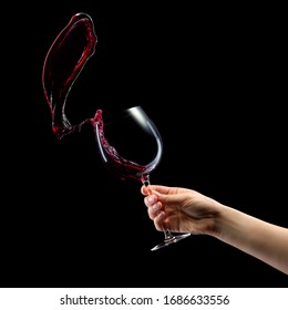 Woman Hand Holding Red Wine Glass With Splashes Isolated On Black Background With Clipping Path