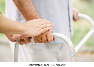 woman hand holding hand of senior man to support while using walker