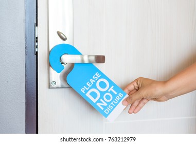 Woman Hand Holding Signboard Do Not Disturb Hanging On The Door.