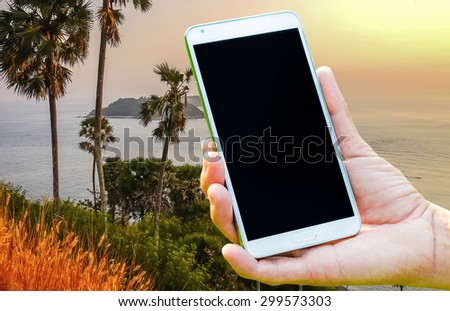 Woman hand holding smartphone against on nature of sunset background soft focus.