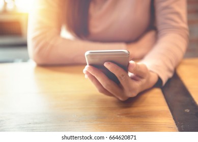 Woman Hand Holding Smartphone At Modern Coffee Shop, She Watching Video On Mobile Phone.