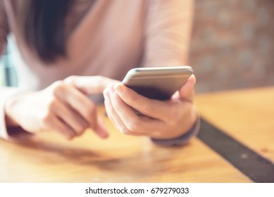 Woman hand holding smartphone at modern coffee shop, She using application on mobile phone.