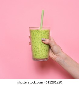 Woman Hand Holding Smoothie Shake Against Pink Wall. Drinking Green Healthy Smoothie Concept.
