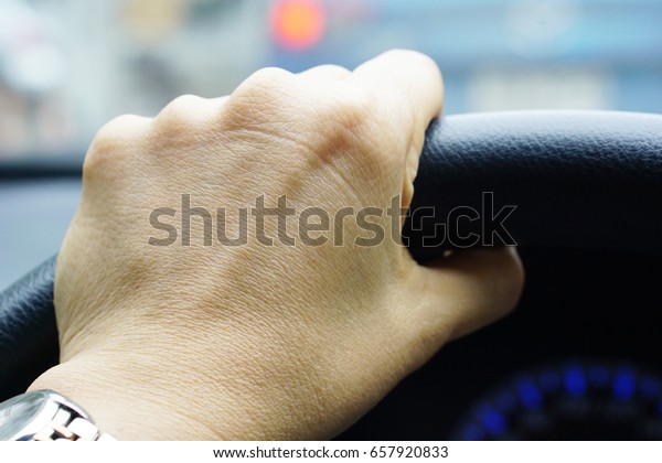 Woman hand holding steering\
wheel