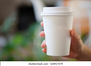 Woman Hand Holding White Paper Cup Of Hot Coffee In Cafe.