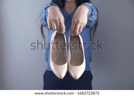 woman hand holding white shoes on grey background