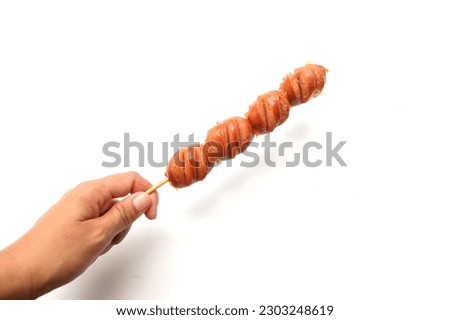 woman hand holding wooden skewer with sausage or Mini cocktails on bamboo skewers isolate on a placed on a white backdrop.One of Thai tasty barbecues commonly seen in street food in Thailand.