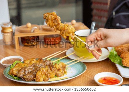 Woman hand holds a (chicken) Pieces of satay (chicken, beef, pork)
