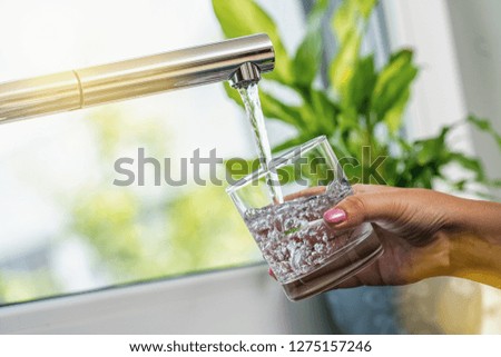 woman hand holds a glass to Filing it with water from tap