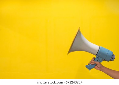 Woman hand holds magaphone,yellow background,copy space,selective focus - Shutterstock ID 691243237