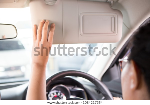 Woman hand holds the\
sun visor in the car