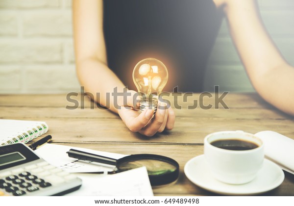 \
woman hand idea or bulb and stationery objects on\
wood table