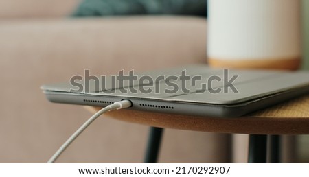 Woman hand inserts the cable to charge the tabletPC on the table. Close-up.