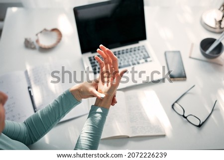 Woman with hand, joint, arm and finger pain, stretching and massaging during work on a laptop. Stockfoto © 