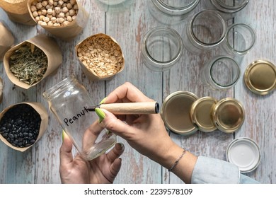 Woman hand labelling recycled glass jar for bulk food. Plastic free and Zero waste concept at home. Overhead top view - Powered by Shutterstock