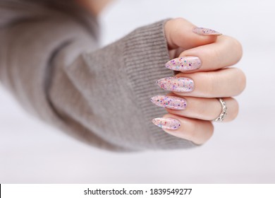 Woman Hand With Long Nails Manicure And Pink Bottle With Nail Polish