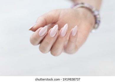 Woman Hand With Long Nails Manicure And Light Pink Bottle With Nail Polish