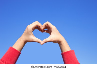 Woman Hand Making Sign Heart In Red Cloth Over The Sky