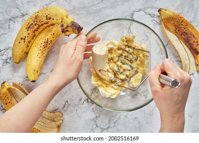 Woman hand mashing up several bananas to bake into a banana bread. - Shutterstock ID 2002516169