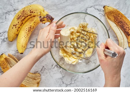 Woman hand mashing up several bananas to bake into a banana bread.