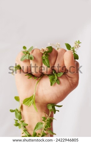 Woman hand, nature growth and fist for eco warrior, fight and revolution for sustainability protest. White background, studio and person with leaf and green plant in hands for environment rally