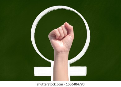 A woman hand on green chalkboard and feminist icon  - Powered by Shutterstock