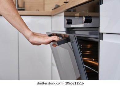 Woman hand open electric oven door with handle. Homemade cooking. Kitchen appliance