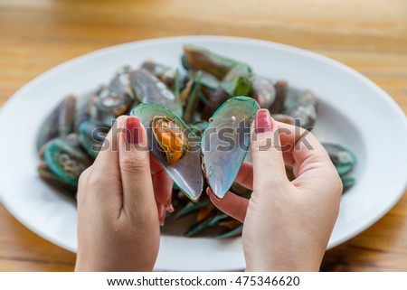 Woman hand open green mussel with white disk background