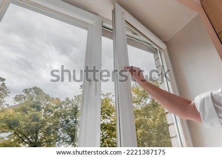 woman hand open pvc window with double glazing. Room ventilation concept
