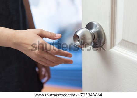 Woman hand is opening the door in the house in the house. The coronavirus or covid-19 and bacteria on the door knob surface.