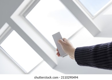 Woman Hand Opening Roof Windows Of A House With Remote Controller. Home Automation