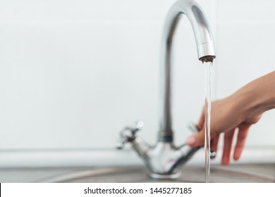 Woman Hand Opening Silver Faucet Or Water Tap With Metal Washing Sink In The Kitchen.