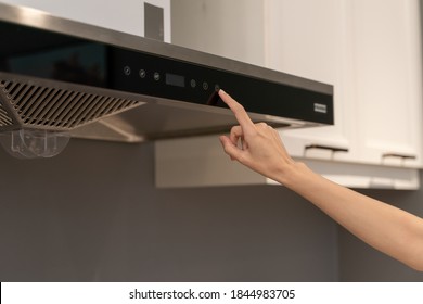 Woman hand opens kitchen hood for cooking. Modern interior.